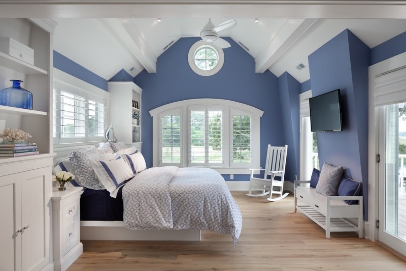 bedroom with blue walls, white vaulted ceiling, white chair, white bench, white cabinet, white bedding, navy blue linen, light blue cover, white framed glass window