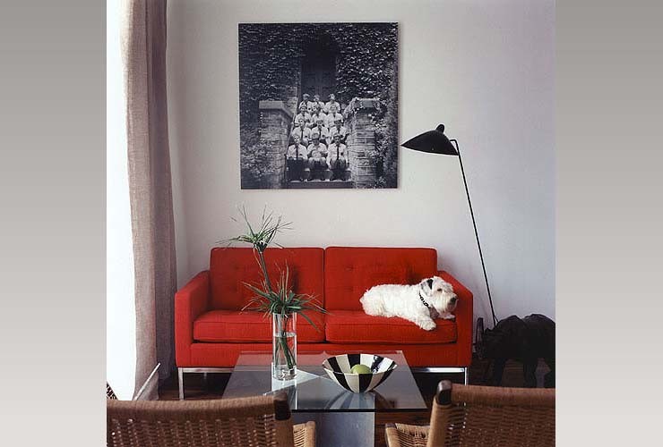 red upholstered sofa with cushion, and rattan chairs, and dark glass coffee table