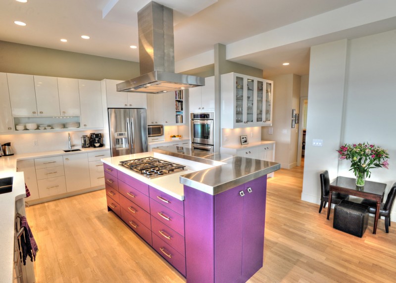 trendy L shaped kitchen idea with deep toned lavender kitchen island with extra storage white flat panel cabinetry stainless steel appliances white backsplash wood floors