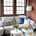 white upholstered sofa with white cushion, colorful pillows, and two white wooden coffee table