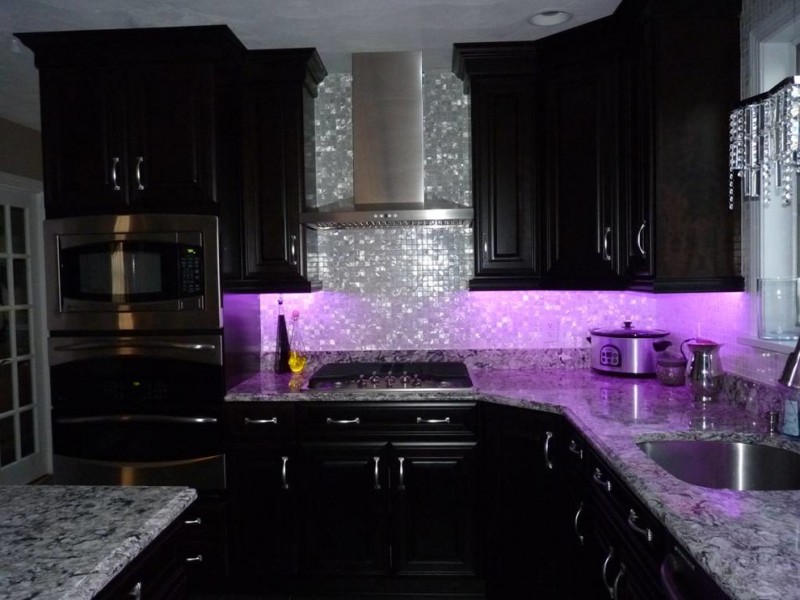 luxurious and glamourous kitchen idea with shiny purple ambiance glowing silver toned backsplash black painted cabinets marble countertop stainless steel appliances