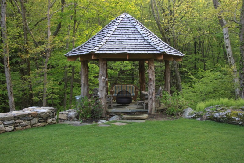 round gazebo with wood block poles, stone flooring, chairs, fire pit, shingles roof