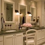 vanity with green granite top, two sinks with makeup area in the middle, white tile in the wall, porcelain tile flooring, white cabinet, white chair,