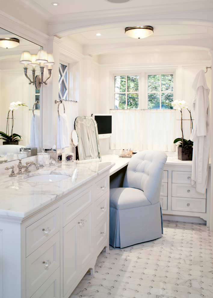 white countertop vanity with under mount sink, large mirror, sconces, makeup area, makeup mirror, grey chair,