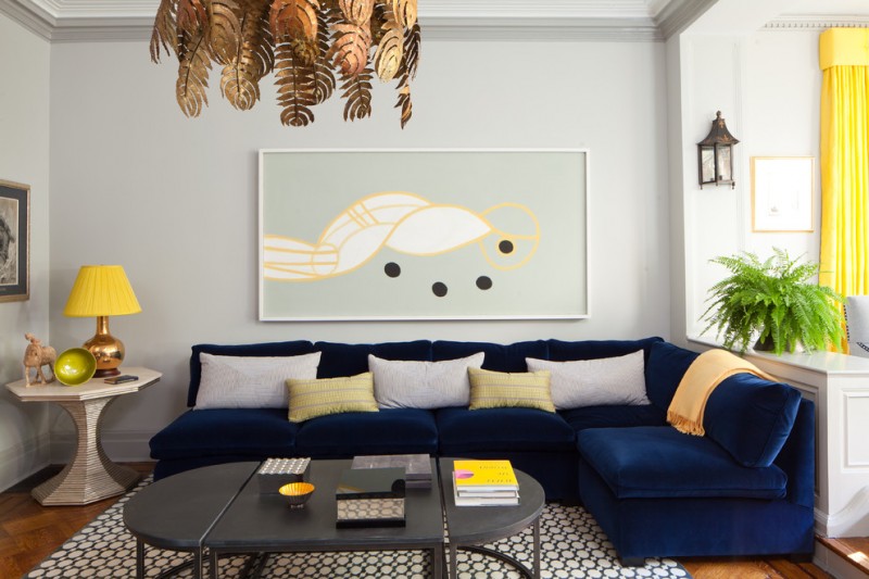 L shape cushion in navy blue white and light yellow decorative pillows abstract hand painting unique side table monochromatic area rug dark hardwood floors light grey wall painting