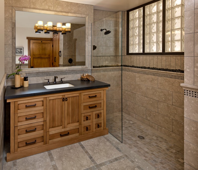 bathroom with walk in shower with limestone flooring, wall, wooden cabinet with granite top, glass partition