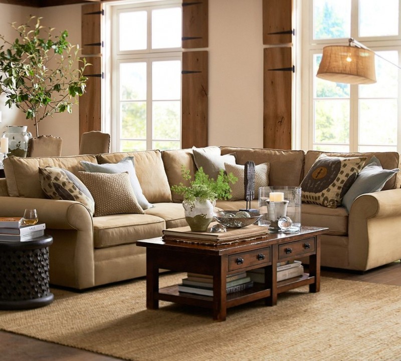 brown pottery barn pearce sofa pillow throws wooden kitcen table cream rug brown floor white and green vase
