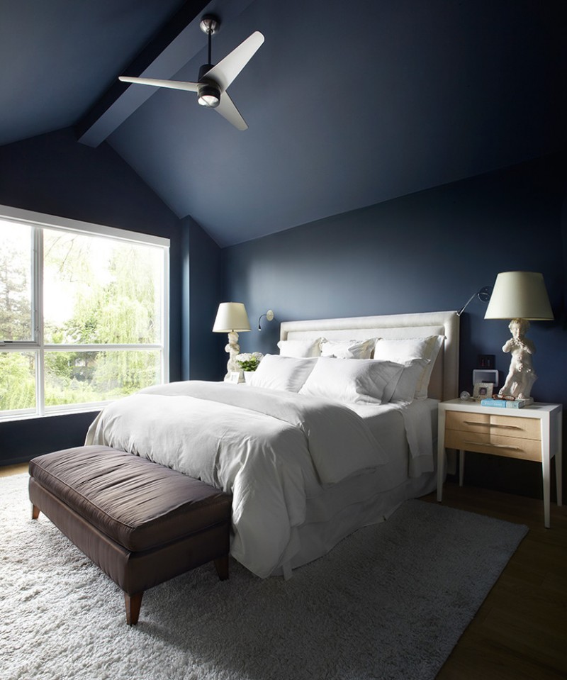 coastal bedroom design with navy blue walls white bedding light wood bedside tables medium toned wood floors gray area rug