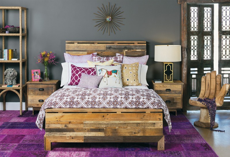 contemporary bedroom design bold patterned & multicolored bedding eclectic wood bedroom furniture bold purple bedroom rug wood bedside tables hand shaped wooden chair wooden vertical shelving unit
