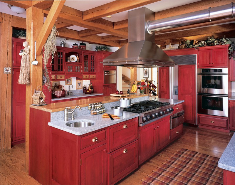 red painted cabinets and doors wooden pillars kitchen island with granite countertop accent rug floating cabinets light toned wooden floors 