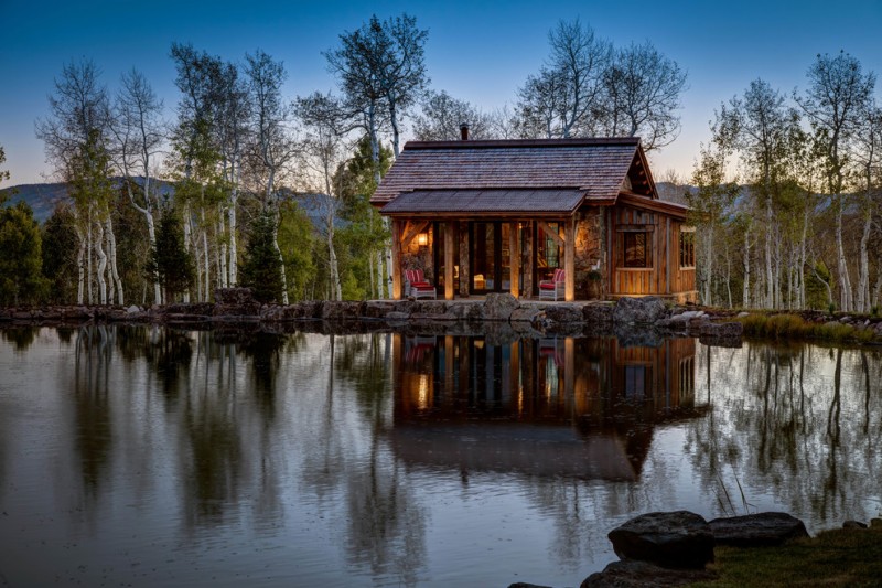 small rustic cabins body of water trees sky chairs lighting roof pillars exterior beautiful location