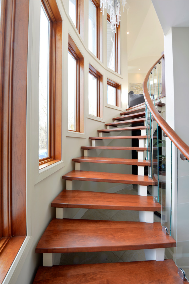 glass stair railing curved stairs wood steps small glass windows beautiful pearls chandelier wood cap white walls