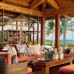 Lanai With Wooden Floor, Wooden Ceiling With Wooden Beams, Wooden Chairs And Sofas With Orange Cushions, Wooden Coffee Table, Pillows