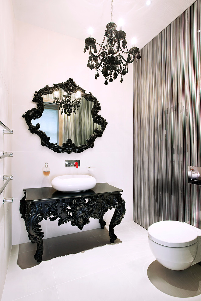 white powder room with white toilet, flooring, wall, dark accented table and mirror, one side of wall in silver