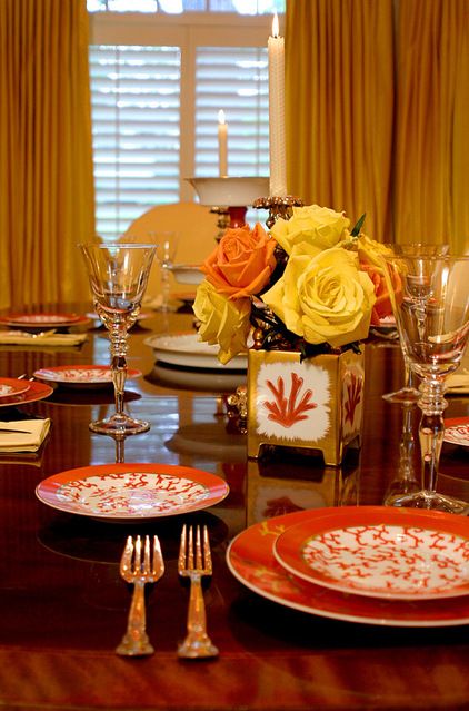 dining table with glossy dark brown table, orange plates, orange and yellow flowers, glasses