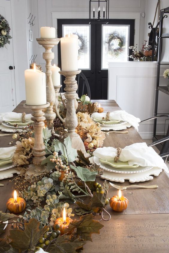 wooden dining table with white plate set, candles, plants, pumpkins accessories