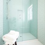 Frameless Shower Door Sweep Blue Porcelain Wall Tiles Chrome Shower Fixture Windows Wooden Stool White Floor Tile Built In Shelves