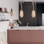 Kitchen With Geometric Pattern On White Tiles On Floor, White Wall, Wooden Shelves, Blak Cupboard On The Back, Pink Island With White Islan Top, Golden Pendant