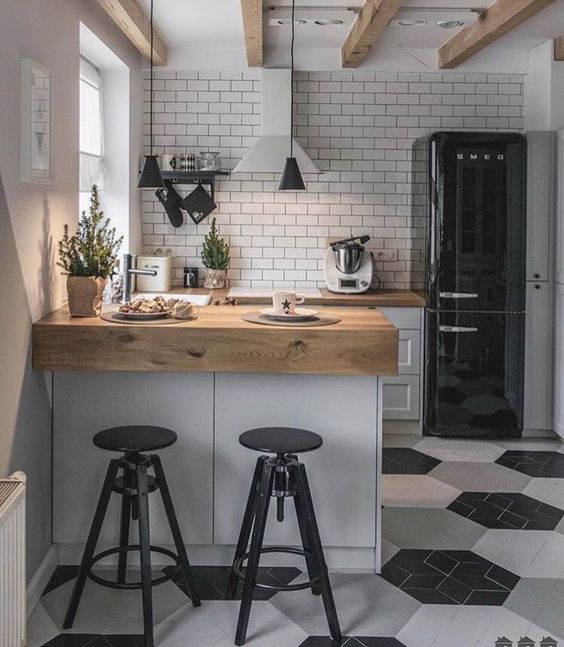 small kitchen with white backsplash, white and black hexagonal tiles floor, white cabinet with brown wooden kitchen top, black stool
