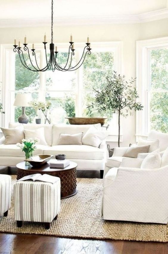 living room, dark wooden floor, white sofa, white wall, white ceiling, black metal chandelier, white ottoman, wooden coffee table