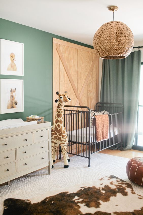 nursery, wooden floor, white rug, animal pattern rug, white cabinet, green wall, wooden accent wall, green curtain, rattan conver chandelier