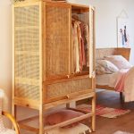 Wooden Rattan Cupboard With Drawer And Tall Legs, Wooden Floor, Rug, Rattan Bed With White Bed, Pillow