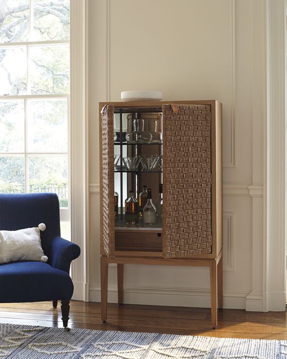 woven cabinet for wine, living room, wooden floor, white wall, blue chair, white pillow