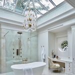 Bathroom, White Marble Floor Tiles, White Tub, Clear Glass Partition, White Chandelier, Clear Glass Roof, White Cabinet And Vanity Table With White Golden Chair