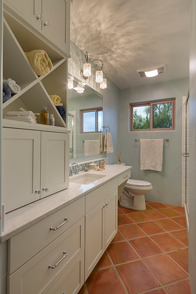 beachy bathroom terra cotta floor tile towel holder window glass showerdoors white cabinet glass wall sconce toilet sink wall mirror