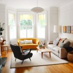 Living Room, Wooden Floor, Brown Rug, Yellow Sofa, Brown Sofa, Black Chair, Wooden Coffee Table, White Wall, Windows On Alcove, White Floor Lamp, White Pendant