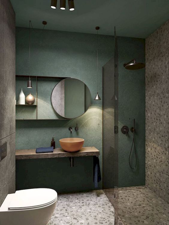 bathroom, grey terrazzo floor and wall tiles, green painted wall, round mirror, floating vanity, orange round sink, round mirror, grey wall, white floating toilet