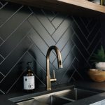 Black Herringbone Backsplash Tiles, Wooden Floating Shelves, Black Top, Black Cabinet With Golden Handler