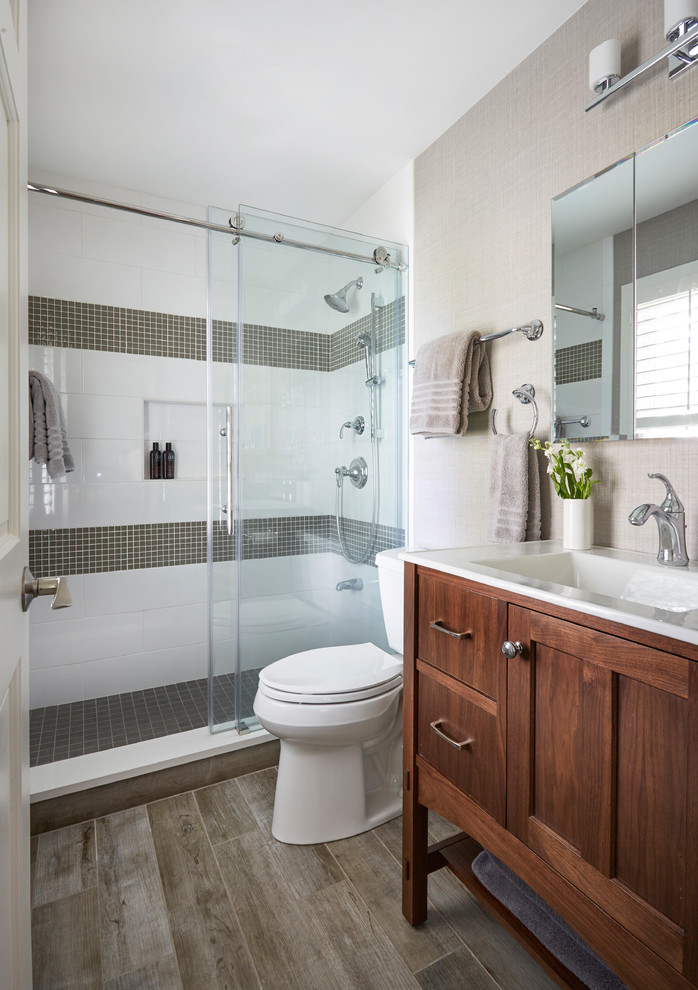 small bathroom white and gray wall tiles wooden floor toilet glass sliding shower doors shower fixtures wall mirror towel holder wooden vanity sink faucet