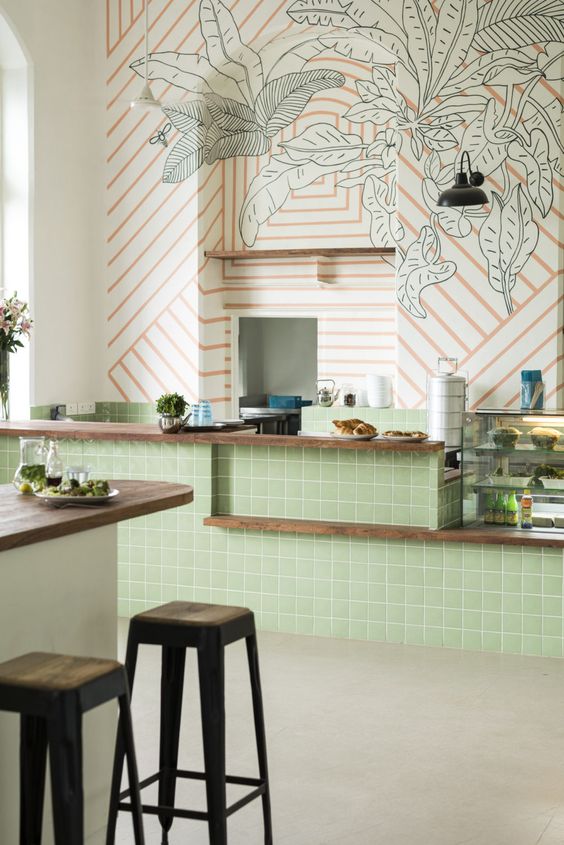 kitchen, beige floor, green tiles island, wooden kitchen top, orange striped with green leave wallpaper, island with wooden top, black stool