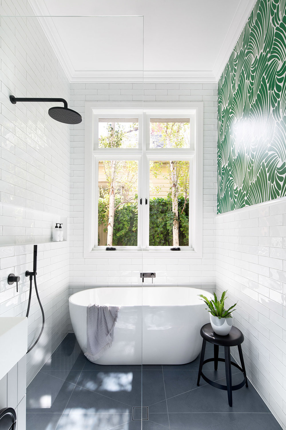 bathroom, white subway wall tiles, grey floor tiles, white tub, white sink, black faucet, green wallpaper accent