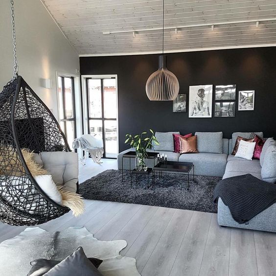 living room, wooden floor, black rug, soft blue sofa, black tray square coffee table, black rattan swing, pendant, black wall, white wall