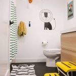 Bathroom, Black Tiny Hexagonal Tiles, White Wall, White Toilet, Wooden Cabinet, White Top, Striped Curtain, Yellow Stairs