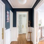 Hallway, Wooden Floor, White Wainscoting, Dark Blue Wall, White Ceiling, White Door, White Pendant