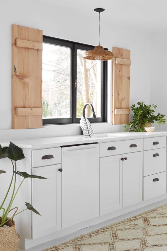 kitchen, white bottom cabinet, white wall, white counter top, wooden window, black framed window, cream rug
