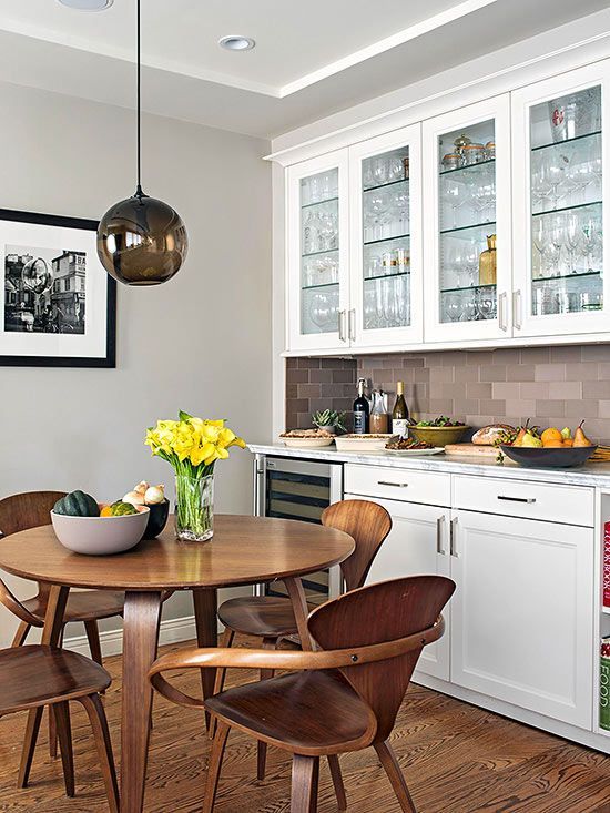 open kitchen, wooden floor, dark wooden dining set, black bulb pendant, white cabinet, brown subway backsplash