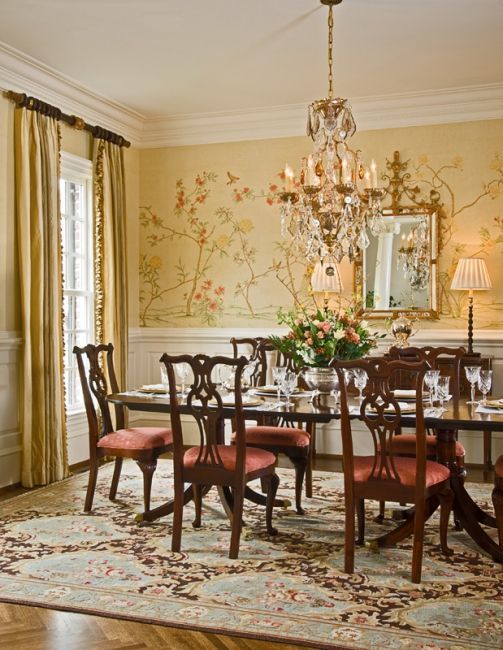 dining room, patterned rug, yellow wall, flowery pattern, wainscoting, chandelier, wooden chairs, round table