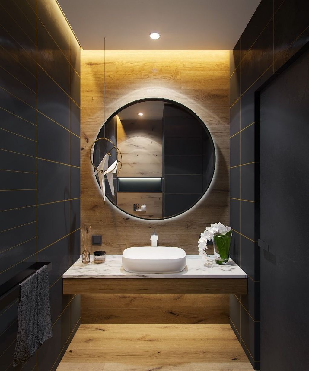 floating vanity with white marble top, white sink, wooden accent wall and floor, black wall with golden lines, round mirror