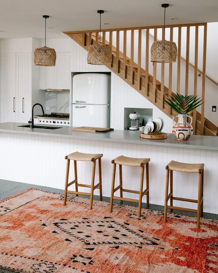 kitchen, grey floor, white wooden island, grey top, wooden wall, wooden stairs, rattan pendant, wooden stools