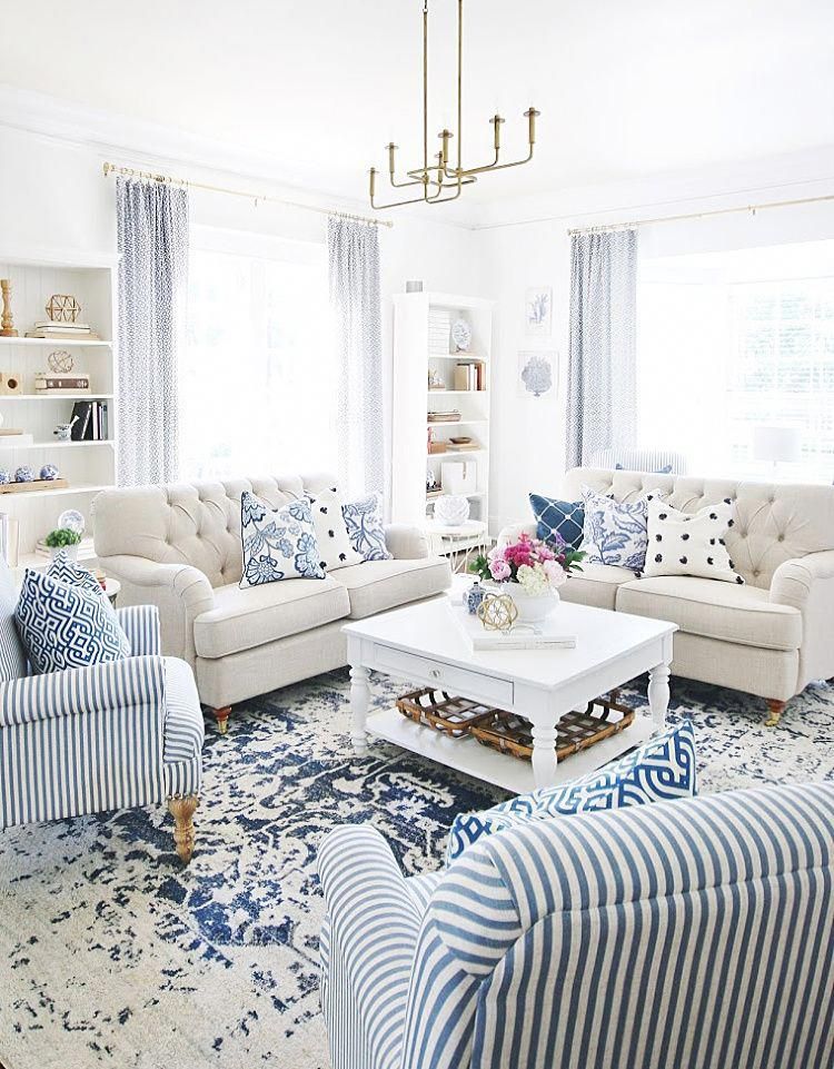 living room, blue pattterned rug, blue white striped chair, white wooden coffee table, off white sofa, white wall, white shelves