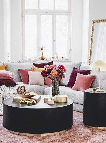 living room, pink rug, black round coffee table, black side table, grey sofa, pink grey red pillows, white wall