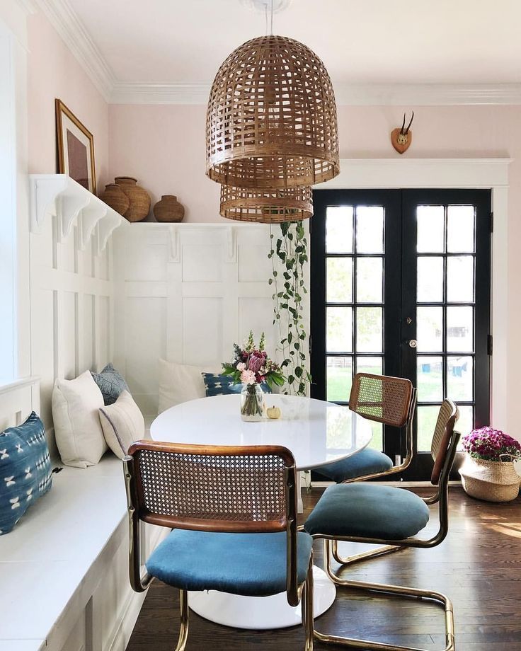 banquette, dark wooden floor, white wall, white floating shelves, white built in bench, round white table, chopper chairs with blue cushion