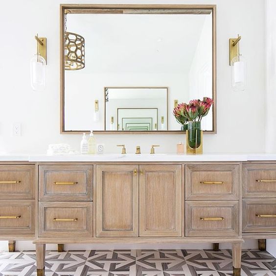 bathroom, white wal, wooden cabinet, mirror, white top, sconces with glass and white accent inside