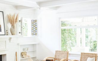 living room, wooden floor, brown rug, white wall, rattan chairs, wooden coffee table, white built in shelves, white sofa, white beamed ceiling